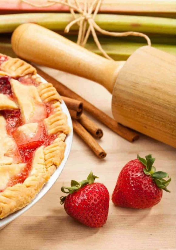 Rhubarb strawberry pie and wooden rolling pin fresh strawberries and four cinnamon stix
