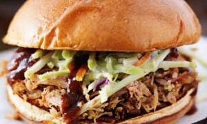 pulled pork on crusty bun with coleslaw and bbq sauce