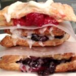 A stack of pastries with berries and cream.