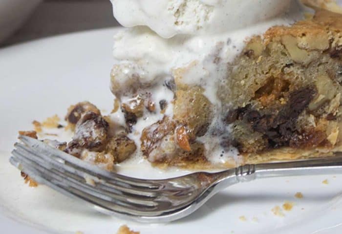 chocolate chip cookie pie with bite removed, fork to the side and ice cream over all