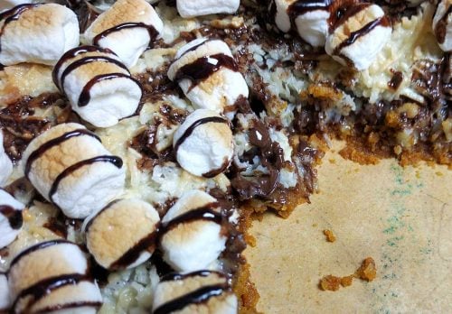 magic cookie bar pizza with slice removed on a pizza stone