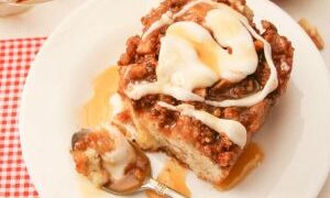 big slice of apple pie coffee cake on a white plate, with spoon, walnuts and apple to the side