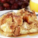 french toast bake on a white plate with grapes and orange juice in the background