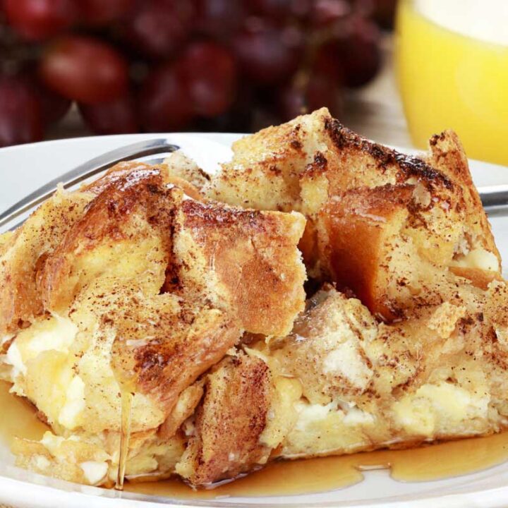 french toast bake on a white plate with grapes and orange juice in the background
