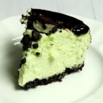 slice of instant pot mint chocolate cheesecake with dark chocolate ganache on a white plate