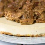 eggnog cheesecake side view on blue plate with praline topping