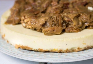 eggnog cheesecake side view on blue plate with praline topping