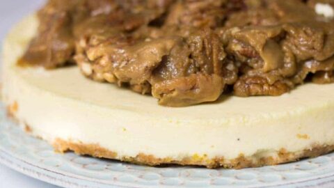 eggnog cheesecake side view on blue plate with praline topping
