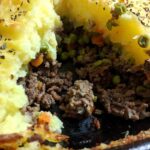 homemade shepherd's pie in cast iron skillet with two servings removed