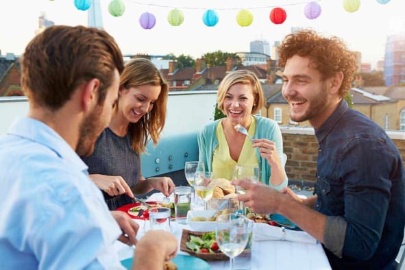 friends, two women, two men dining outdoors, and laughing