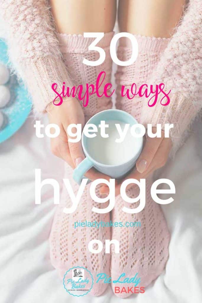 woman's feet with pink socks, arms show a pink sweater with a pale blue mug, with text that says 30 simple ways to get your hygge on.