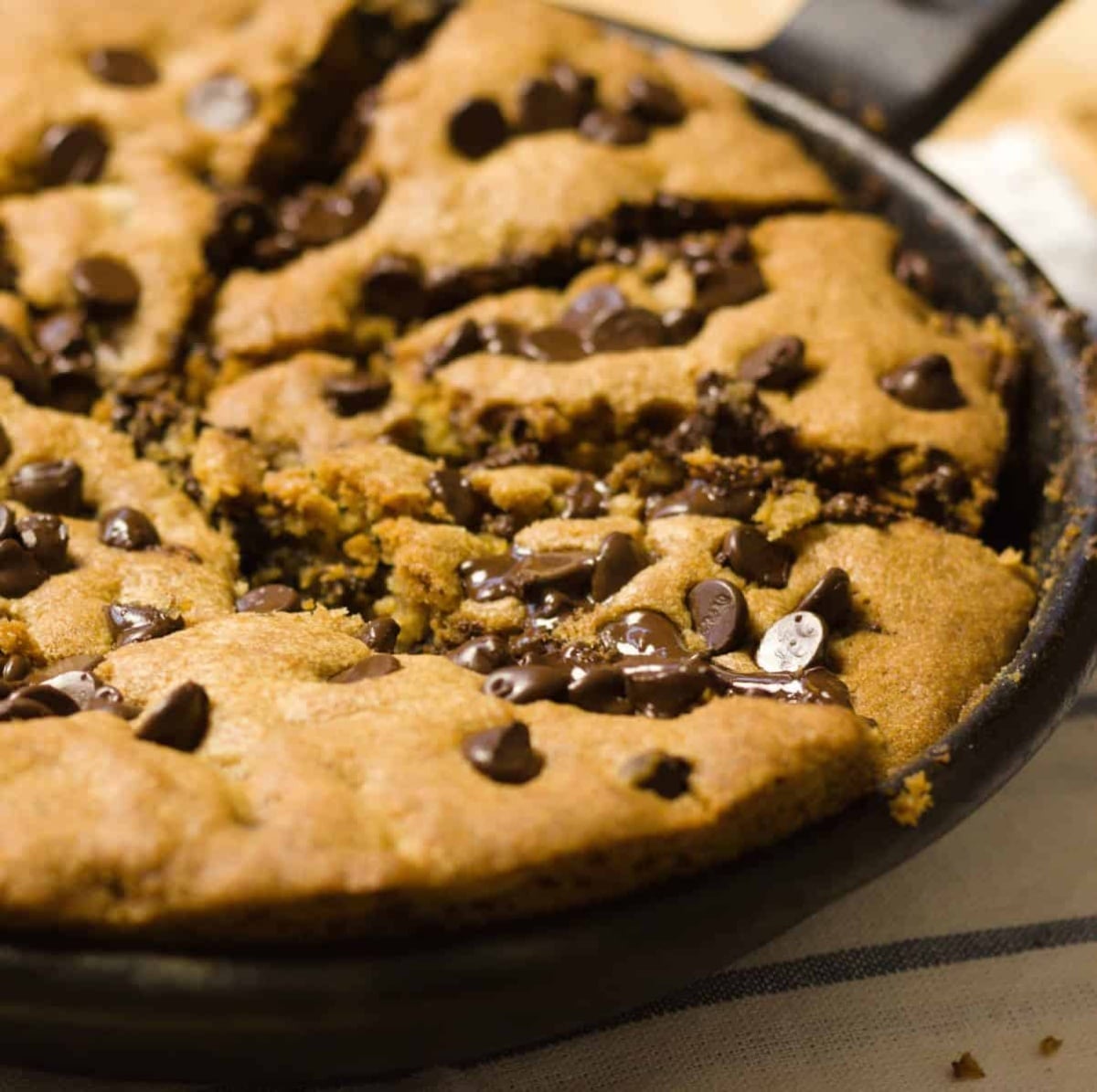 nutella stuffed skillet cookie closeup shows cast iron pan, cookie is sliced ready to eat
