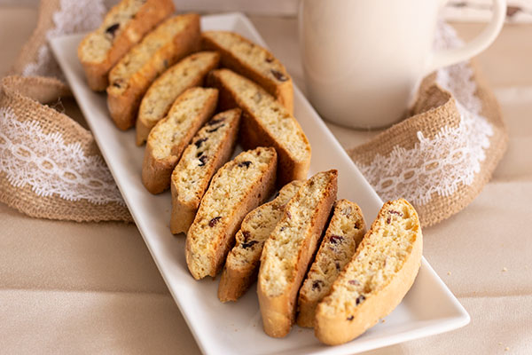 cake mix biscotti on a white dish, burlap & lace ribbon and a white mug in background