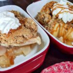 two servings of Mom's apple crisp with whipped cream in red serving dishes