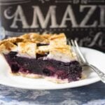 A slice of blueberry pie on a plate with a fork.