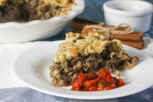 slice of tourtiere (meat pie) on white plate with red relish