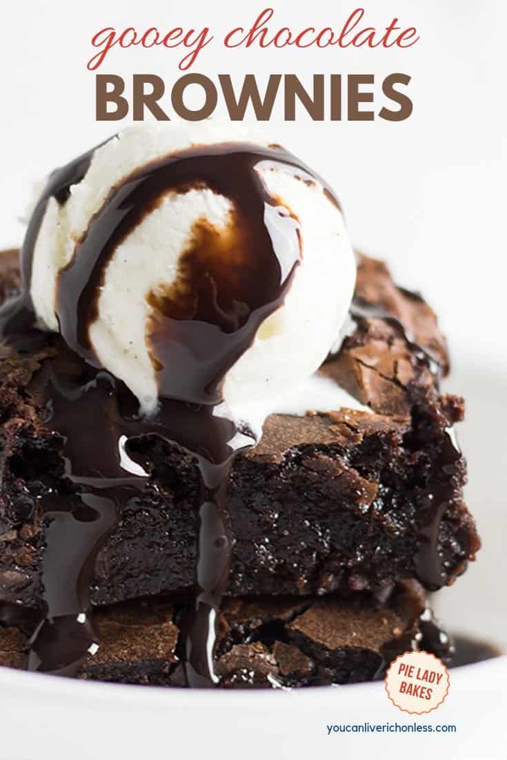 two chocolate fudge brownies in white dish topped with vanilla ice cream and chocolate sauce