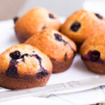 five blueberry muffins on a white napkin with knife