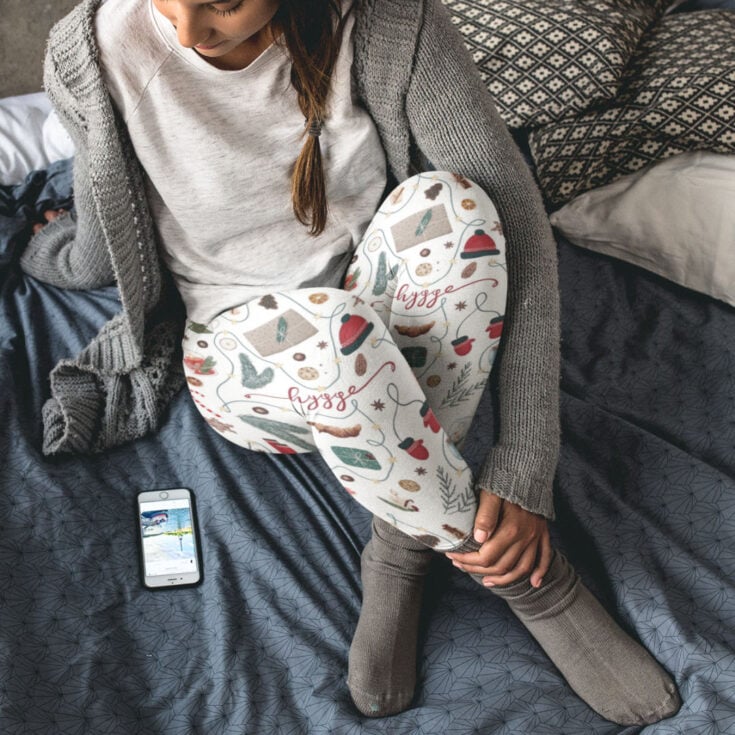 overhead view of woman wearing holiday hygge leggings, socks on a blue blanket