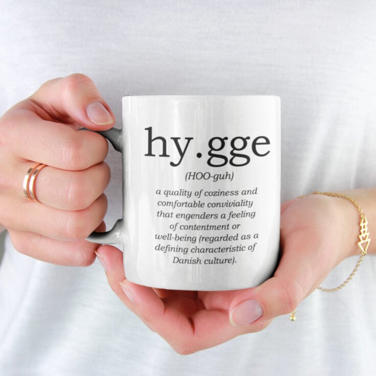hands holding a mug with the definition of hygge printed on it