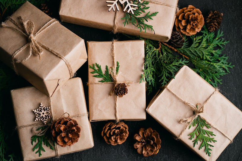 best hygge books with brown paper wrapping on books as gifts with pine cones and greenery, tied with twine