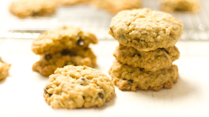 stack and single ranger cookies on a white counter with blurred out cookies on a cooling rack in background
