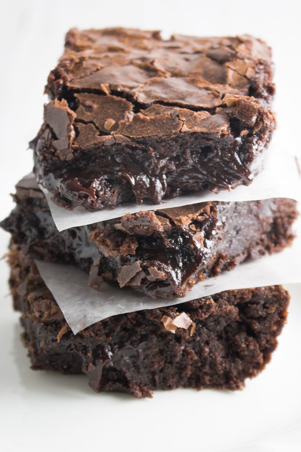 three brownies stacked with waxed paper between each brownie top fudgy brownie has crackly top