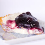 closeup view of no bake blueberry cheesecake pie on square blue plate
