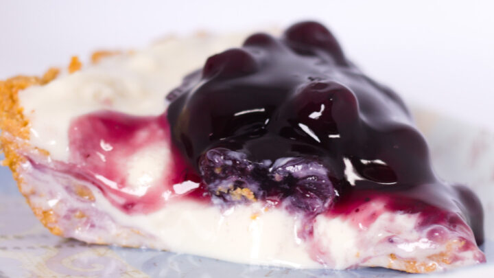 closeup view of no bake blueberry cheesecake pie on square blue plate