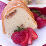 piece of strawberry pound cake on white plate with sliced strawberry square