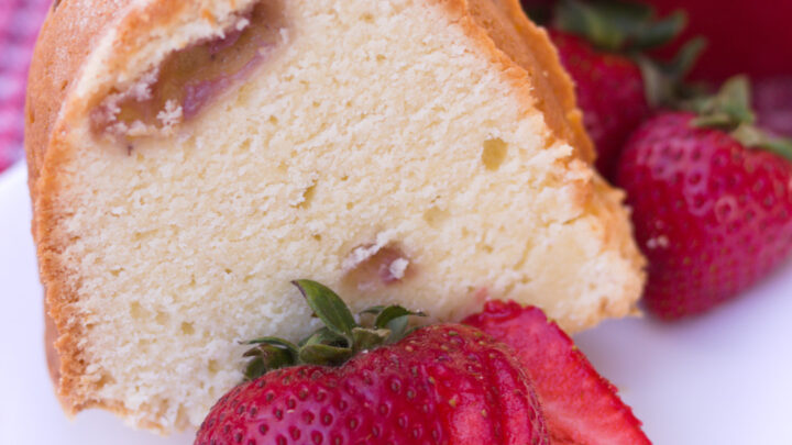 piece of strawberry pound cake on white plate with sliced strawberry square