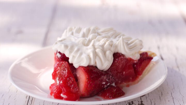 strawberry pie recipe with jello topped with whipped cream on white plate