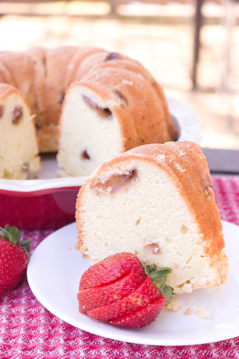 slice of strawberry cream cheese pound cake with sliced strawberry on white plate