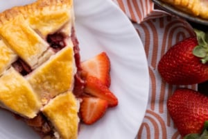 easy strawberry rhubarb pie on white plate overhead with fresh berries