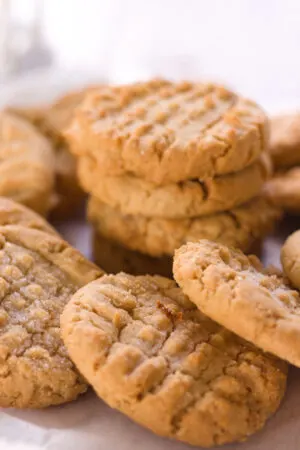pile of soft peanut butter cookies on parchment paper