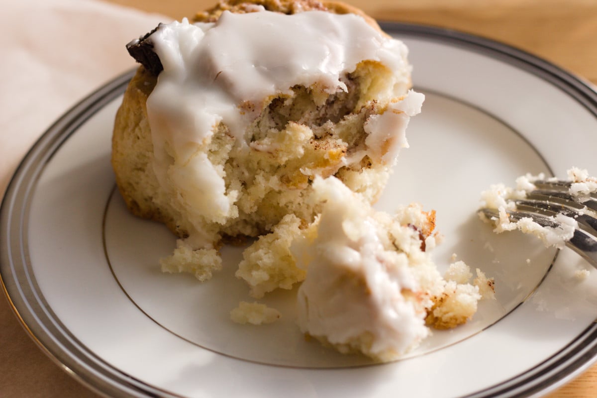bisquick cinnamon roll on white plate with fork being eaten