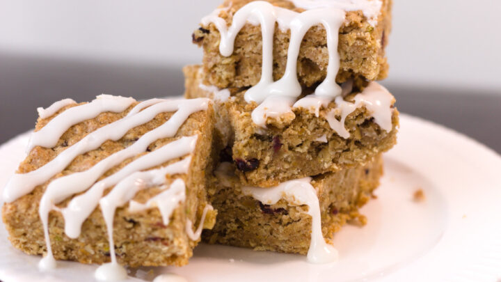 stack of oatmeal squares on white place drizzled with frosting