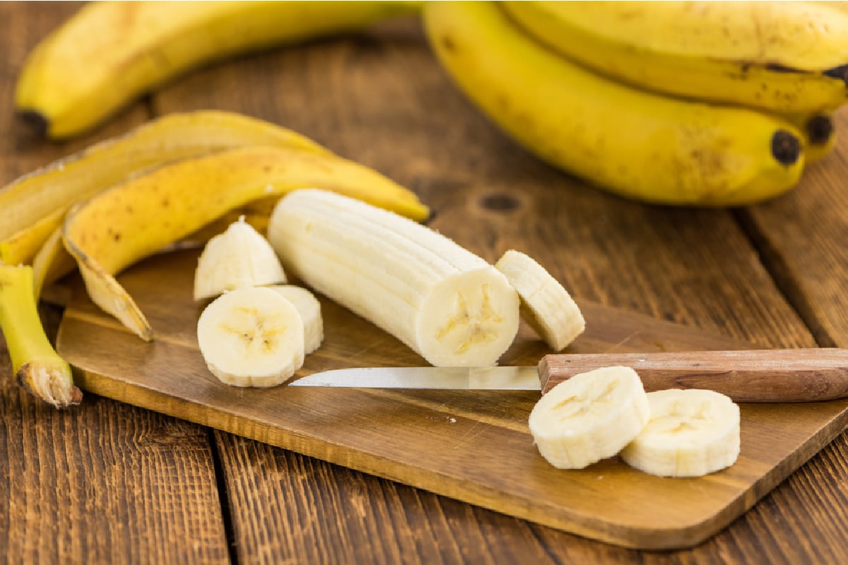 cutting board with sliced bananas knife and banana peels
