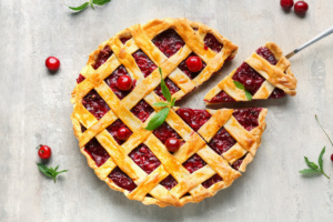 cherry pie with a slice cut on light background