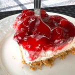 slice of no bake cherry cheesecake pie on white plate with fork