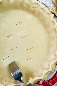 A fork is being used to cut a pie crust.
