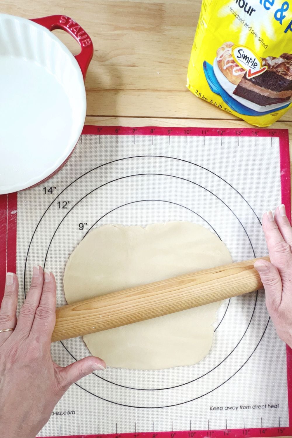 A person using a rolling pin on a baking mat.