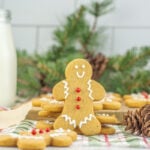 Gingerbread cookies on a table next to a glass of milk.