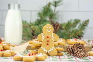 Gingerbread cookies on a table next to a glass of milk.