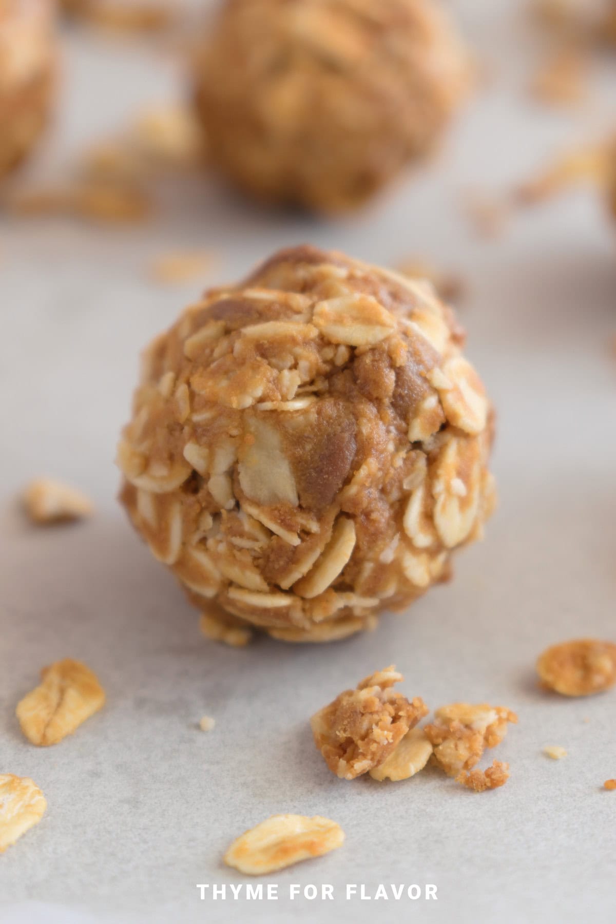 A close-up of an energy bite made with oats and nut butter, resting on parchment paper with scattered oat flakesโone of the best budget-friendly dessert recipes for a quick, wholesome treat.