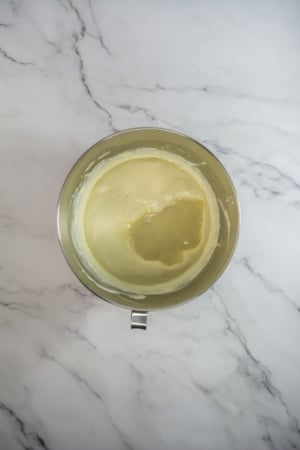 Top-down view of cake batter in a glass bowl on a marble countertop.