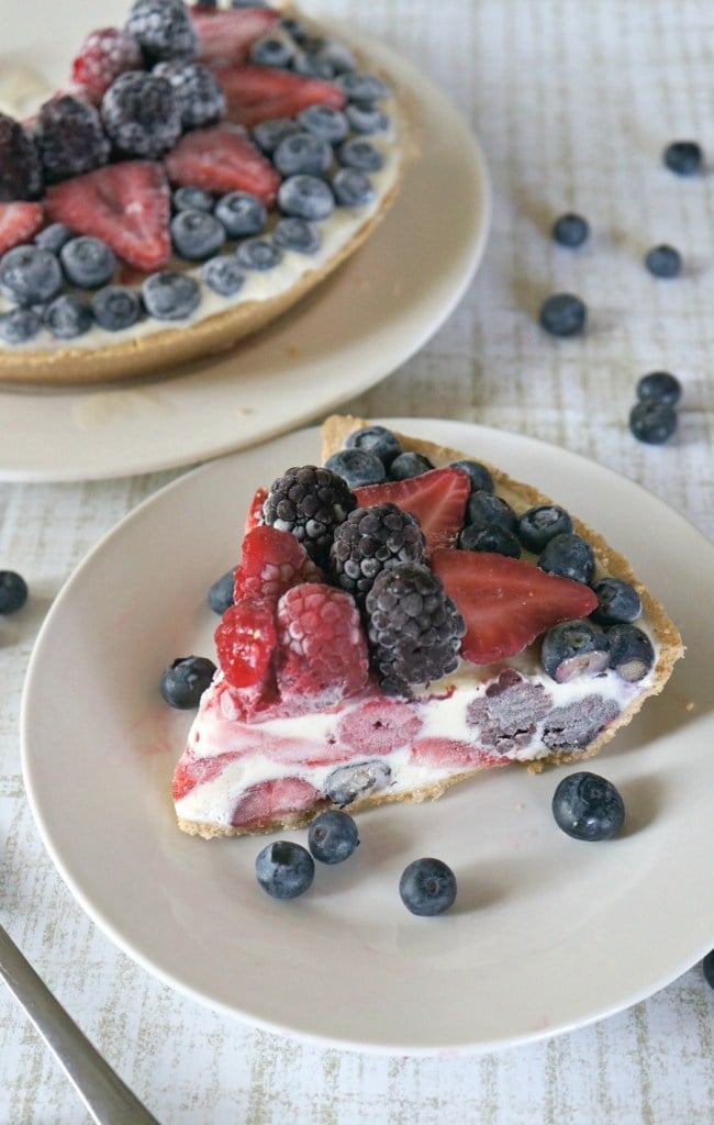 A slice of berry-topped creamy pie sits on a plate, surrounded by scattered berries—a tempting treat perfect for National Pie Day or anyone searching for easy pie recipes.