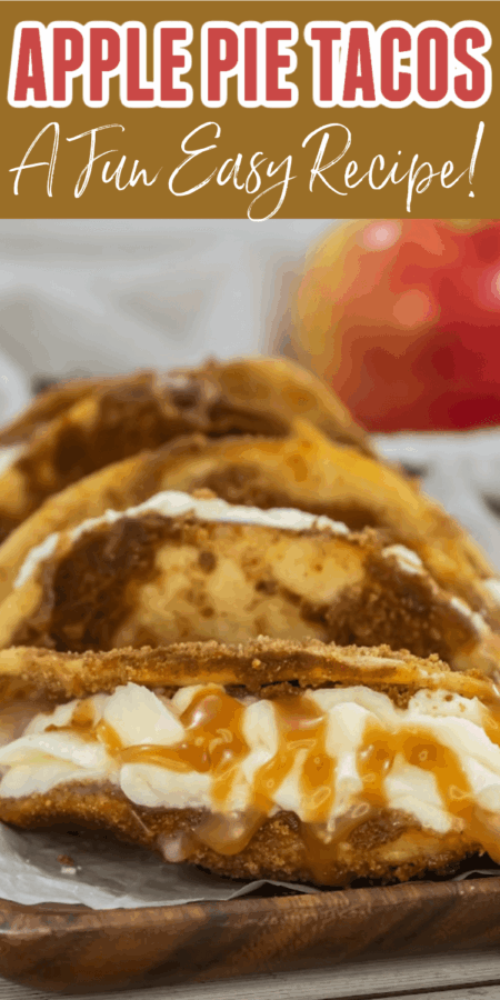 Four apple pie tacos filled with cream and caramel sauce are arranged on a wooden board, with an apple in the background.