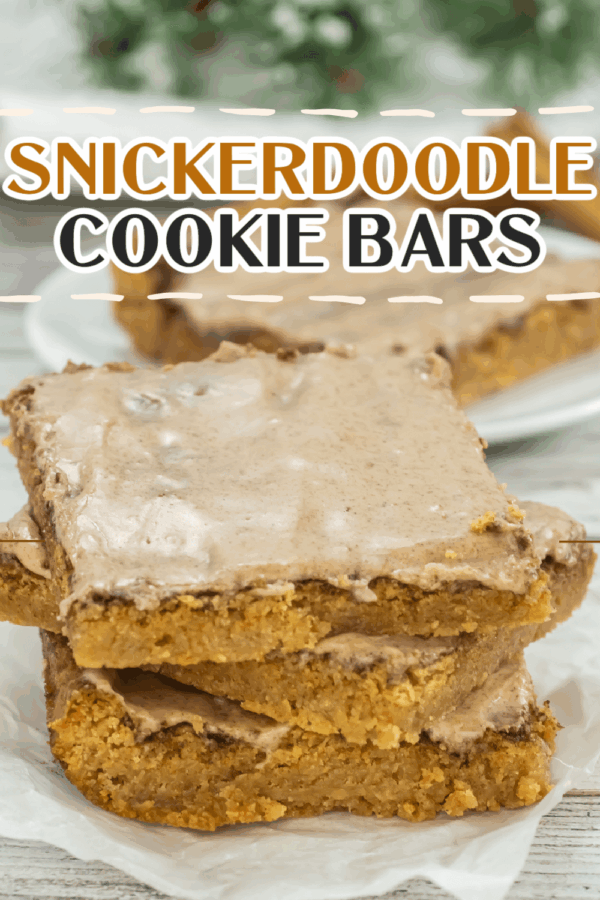Three snickerdoodle cookie bars with cinnamon frosting are stacked on parchment paper, with more bars and greenery in the background. The text reads "Snickerdoodle Cookie Bars.