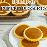 A plate of mini pumpkin tarts is displayed on a white wooden table, with more tarts on a tray in the background. Text reads “Holiday Pumpkin Desserts.”.